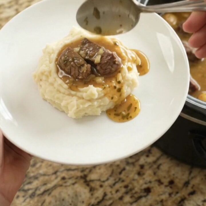 Slow cooker full of tender beef tips and golden potatoes in a buttery au jus