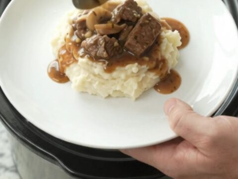 Beef tenderloin tips in a rich garlic-herb butter sauce with mushrooms and onions, served in a slow cooker.
