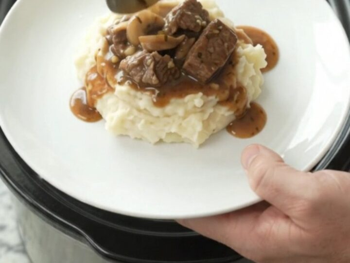 Beef tenderloin tips in a rich garlic-herb butter sauce with mushrooms and onions, served in a slow cooker.