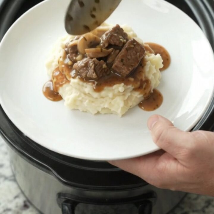 Beef tenderloin tips in a rich garlic-herb butter sauce with mushrooms and onions, served in a slow cooker.
