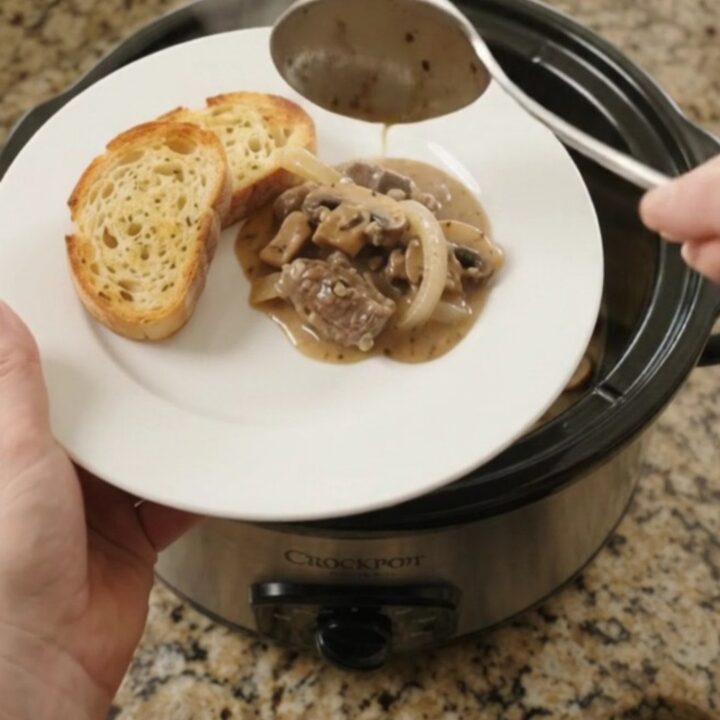 Slow cooker beef tenderloin tips in creamy mushroom Gruyère sauce, topped with melted cheese and mushrooms.
