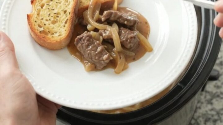 Slow cooker filled with beef tenderloin tips in creamy Gruyère sauce with caramelized onions