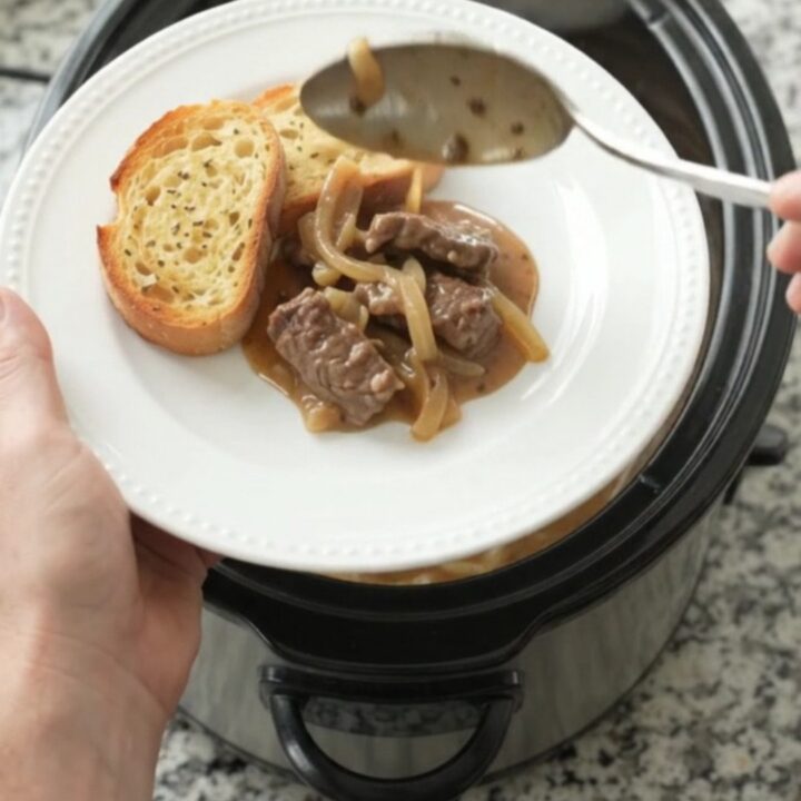Slow cooker filled with beef tenderloin tips in creamy Gruyère sauce with caramelized onions