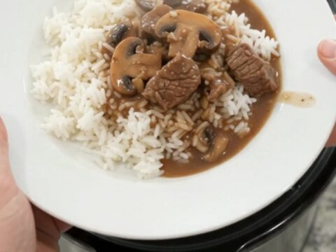 Slow cooker full of beef tenderloin tips, portobello mushrooms, and shallots in bourbon gravy