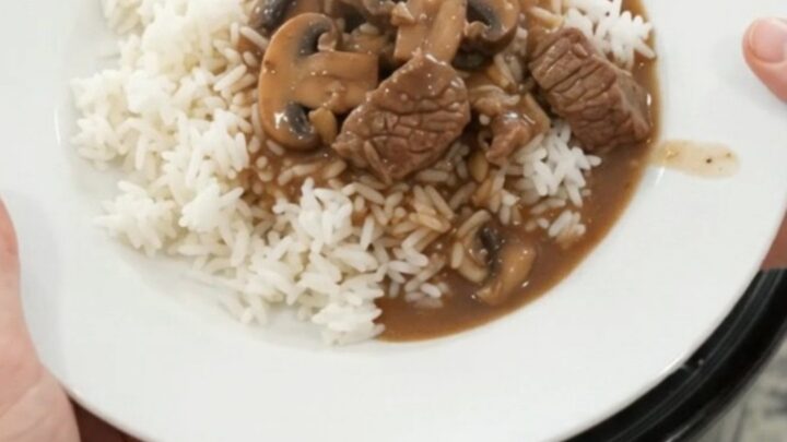 Slow cooker full of beef tenderloin tips, portobello mushrooms, and shallots in bourbon gravy