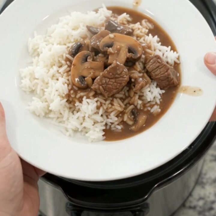 Slow cooker full of beef tenderloin tips, portobello mushrooms, and shallots in bourbon gravy