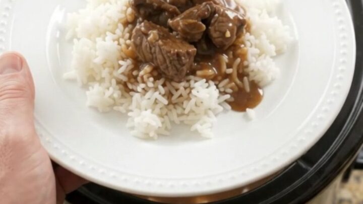 Slow cooker filled with beef tenderloin tips, carrots, and potatoes in bourbon gravy