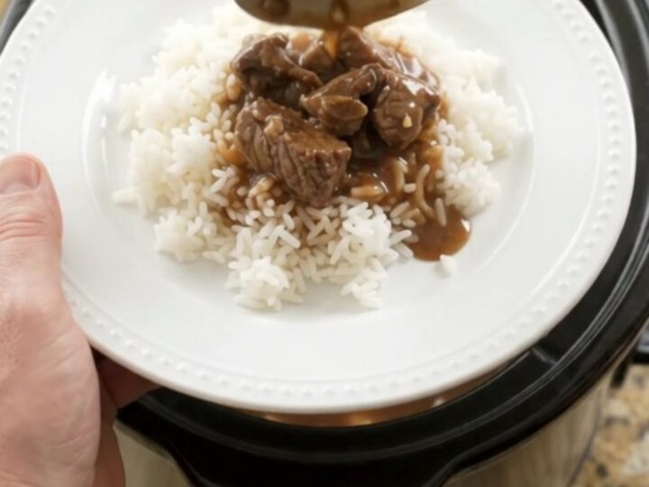 Slow cooker filled with beef tenderloin tips, carrots, and potatoes in bourbon gravy