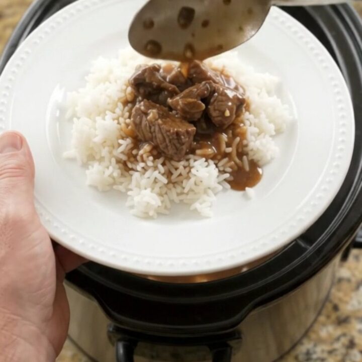 Slow cooker filled with beef tenderloin tips, carrots, and potatoes in bourbon gravy