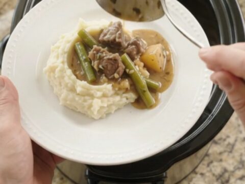 Slow cooker filled with beef tenderloin tips, green beans, and potatoes in a golden garlic-herb butter sauce