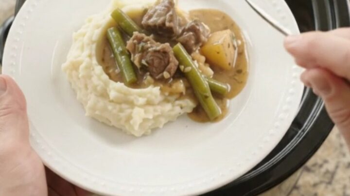 Slow cooker filled with beef tenderloin tips, green beans, and potatoes in a golden garlic-herb butter sauce