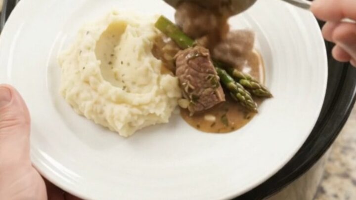 Slow cooker filled with beef tenderloin tips and asparagus in a buttery au jus