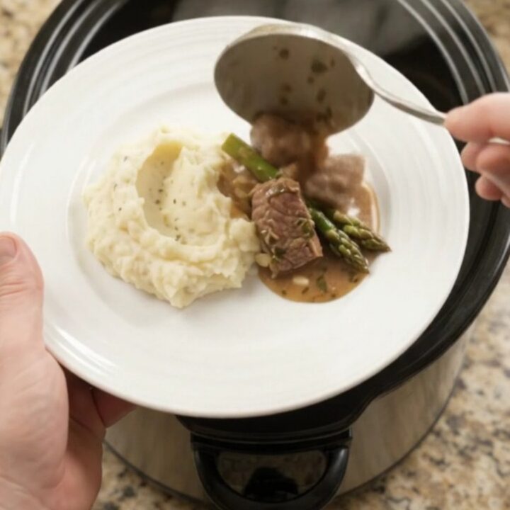Slow cooker filled with beef tenderloin tips and asparagus in a buttery au jus