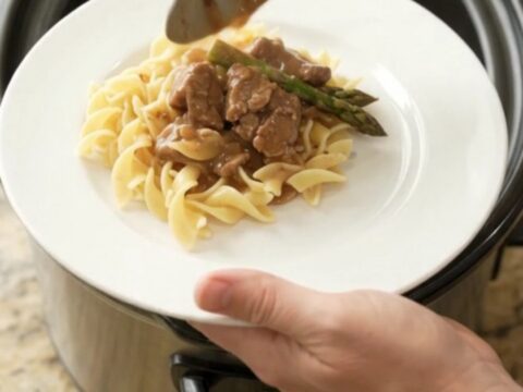 Slow cooker filled with tender beef tips and asparagus in a rich brown gravy