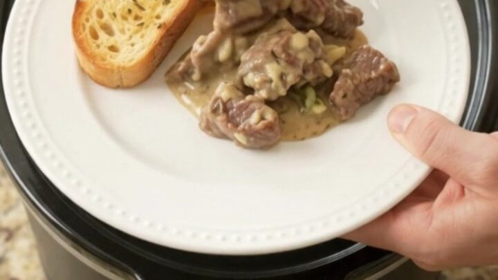 Slow cooker beef tenderloin tips and asparagus in a creamy Gruyère sauce, bubbling in a black crock.