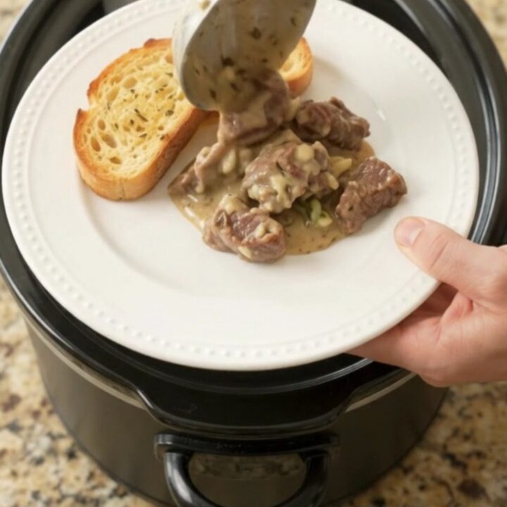 Slow cooker beef tenderloin tips and asparagus in a creamy Gruyère sauce, bubbling in a black crock.