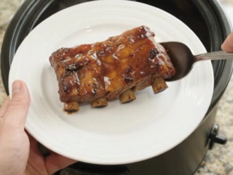Slow-cooker baby back ribs with apples and molasses glaze, garnished with fresh herbs.