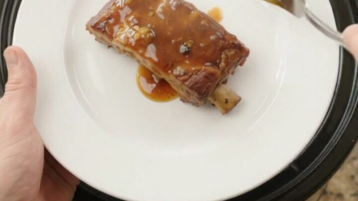 Slow-cooker baby back ribs with pineapple rings and maple bourbon sauce, glistening and tender.