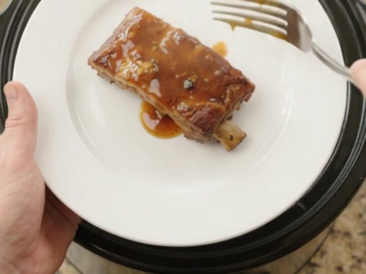 Slow-cooker baby back ribs with pineapple rings and maple bourbon sauce, glistening and tender.