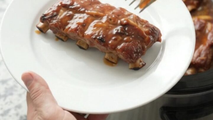 Slow-cooker baby back ribs glazed with smoky chipotle honey hickory sauce, served on a white plate.