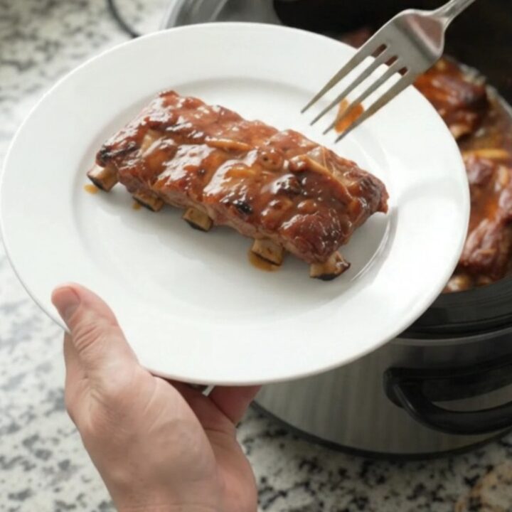 Slow-cooker baby back ribs glazed with smoky chipotle honey hickory sauce, served on a white plate.