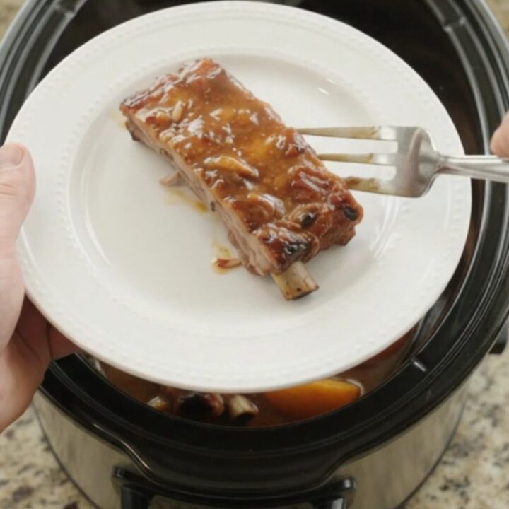 Slow cooker pork ribs with peaches and bourbon BBQ sauce, glistening and tender