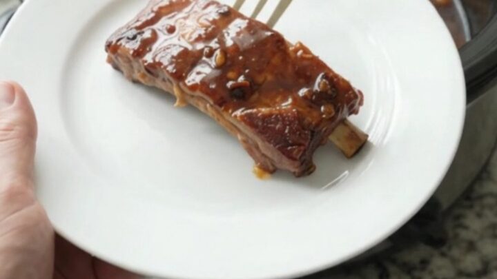 Cherry cola molasses ribs in a slow cooker with glossy dark sauce and cherries