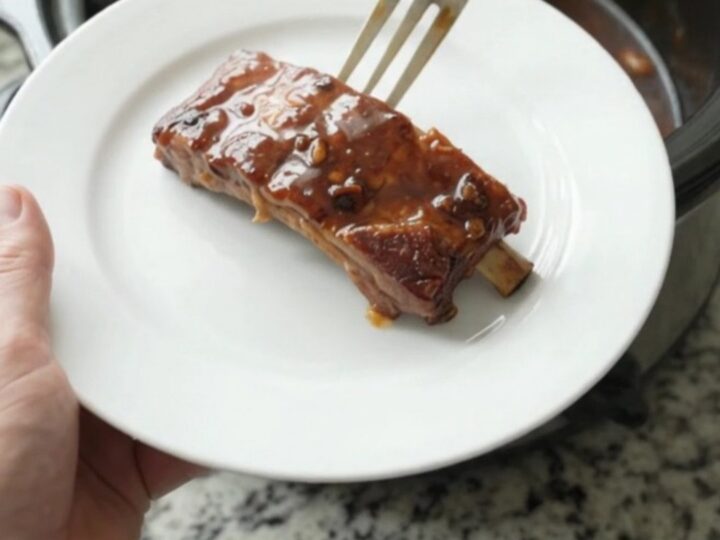 Cherry cola molasses ribs in a slow cooker with glossy dark sauce and cherries