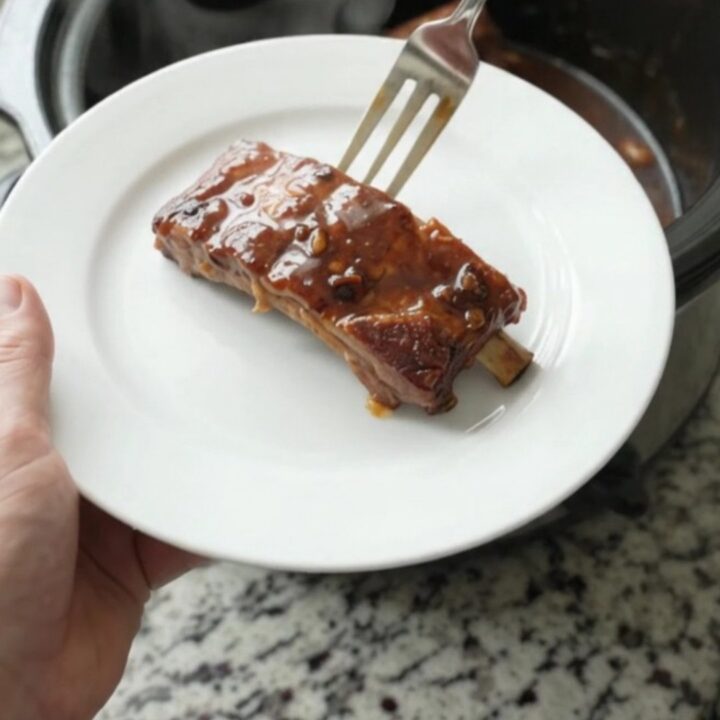 Cherry cola molasses ribs in a slow cooker with glossy dark sauce and cherries