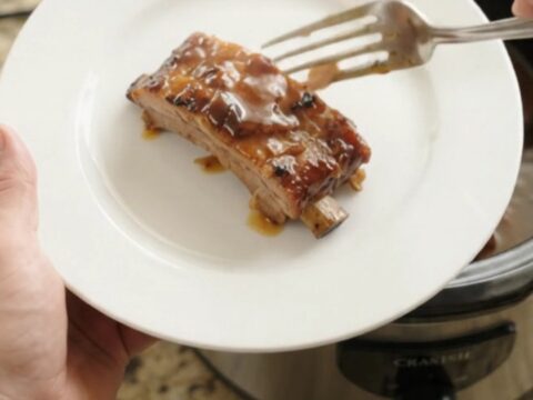 Slow cooker full of glazed baby back ribs in bubbling sauce
