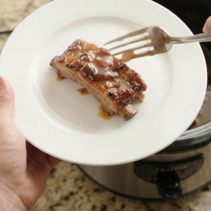 Slow cooker full of glazed baby back ribs in bubbling sauce