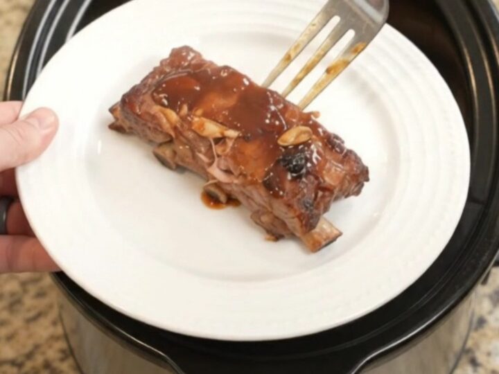 Slow cooker baby back ribs glazed with BBQ sauce, garnished with rosemary