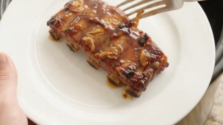 Slow-cooker baby back ribs with garlic and rosemary in a black Crockpot, glazed with honey hickory sauce