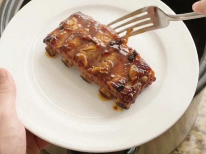 Slow-cooker baby back ribs with garlic and rosemary in a black Crockpot, glazed with honey hickory sauce
