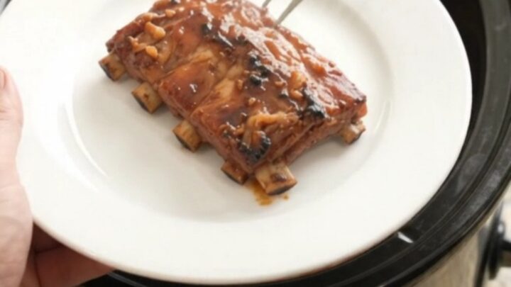 Slow cooker baby back ribs glistening with BBQ sauce and paprika rub