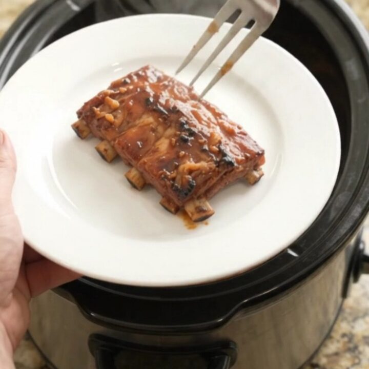 Slow cooker baby back ribs glistening with BBQ sauce and paprika rub