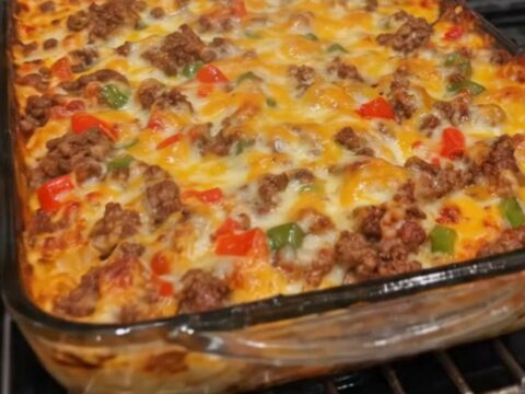 A steaming, golden-brown ground beef casserole in a glass dish with melted cheddar cheese.