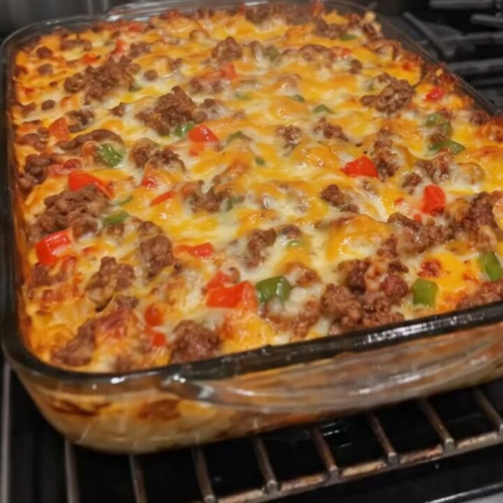 A steaming, golden-brown ground beef casserole in a glass dish with melted cheddar cheese.