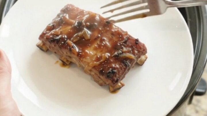 Fall-off-the-bone baby back ribs in a glossy molasses glaze, served on a white plate