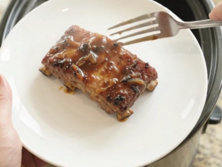 Fall-off-the-bone baby back ribs in a glossy molasses glaze, served on a white plate
