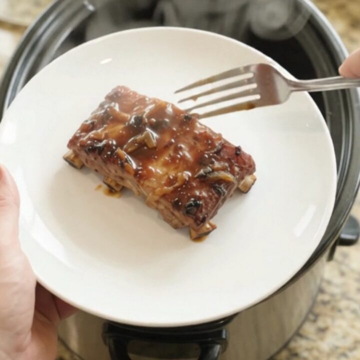 Fall-off-the-bone baby back ribs in a glossy molasses glaze, served on a white plate