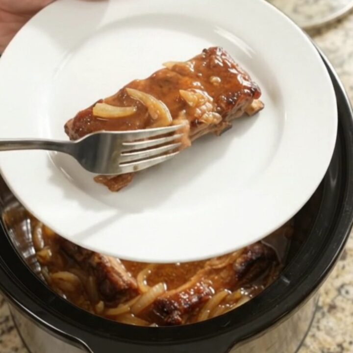 Slow cooker baby back ribs glazed with maple bourbon BBQ sauce and caramelized Vidalia onions