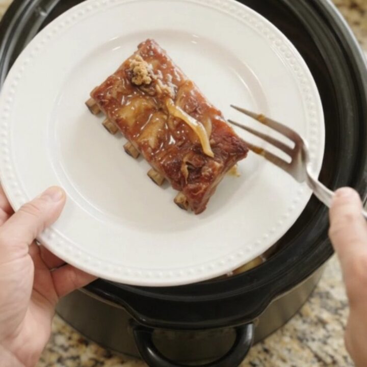 Slow cooker spare ribs glazed with honey hickory barbecue sauce and caramelized onions