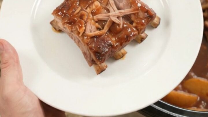 Slow cooker full of glazed spare ribs with apples and BBQ sauce