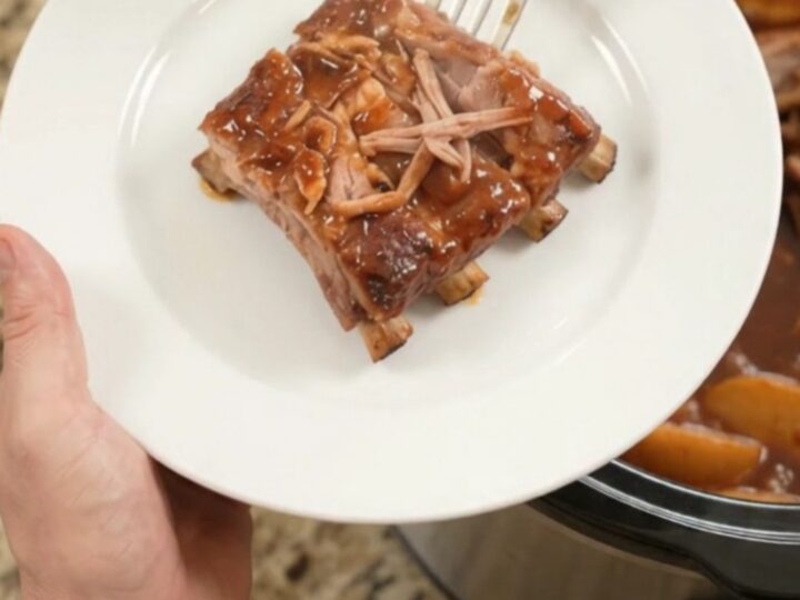 Slow cooker full of glazed spare ribs with apples and BBQ sauce