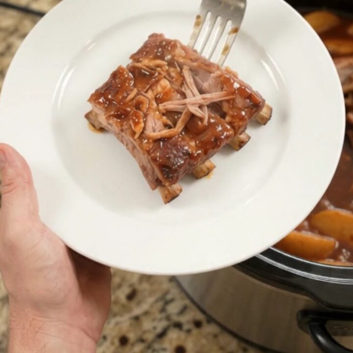 Slow cooker full of glazed spare ribs with apples and BBQ sauce