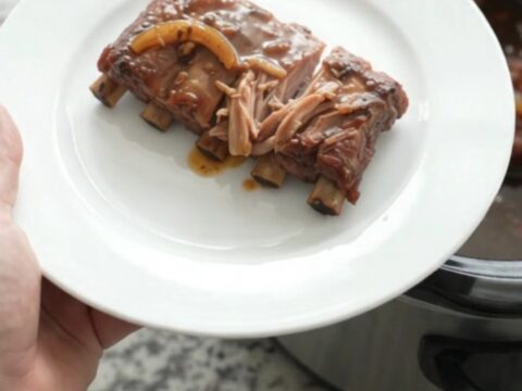 Slow cooker spare ribs glazed with brown sugar molasses sauce, topped with caramelized onions