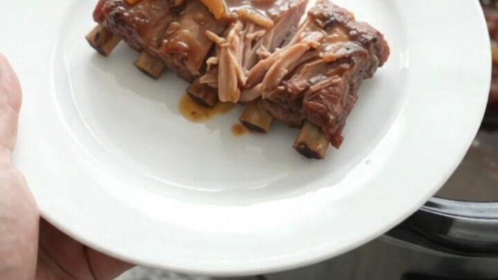 Slow cooker spare ribs glazed with brown sugar molasses sauce, topped with caramelized onions
