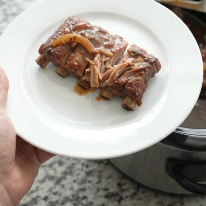 Slow cooker spare ribs glazed with brown sugar molasses sauce, topped with caramelized onions