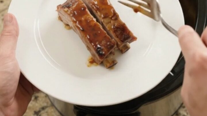 Slow cooker with glazed spare ribs and apples, bubbling sauce, high angle